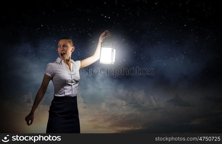 Businesswoman with lantern. Young businesswoman walking in darkness with lantern in hand