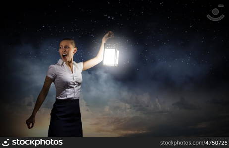 Businesswoman with lantern. Young businesswoman walking in darkness with lantern in hand