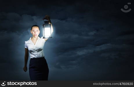 Businesswoman with lantern. Young businesswoman walking in darkness with lantern in hand