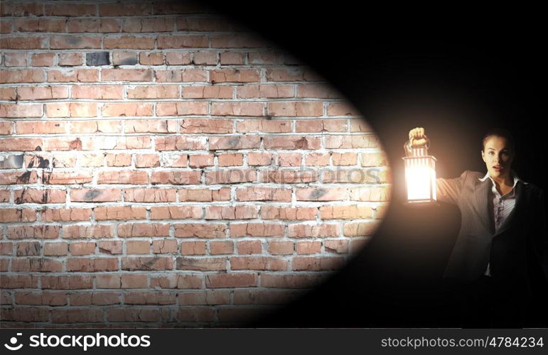 Businesswoman with lantern. Young businesswoman walking in darkness with lantern in hand