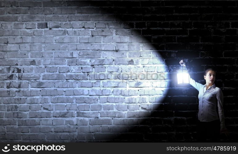 Businesswoman with lantern. Young businesswoman walking in darkness with lantern in hand