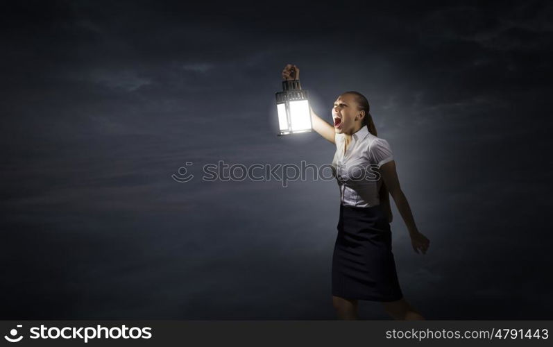 Businesswoman with lantern. Young businesswoman walking in darkness with lantern in hand