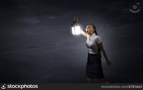 Businesswoman with lantern. Young businesswoman walking in darkness with lantern in hand