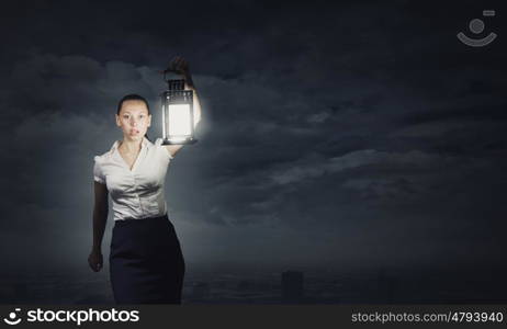 Businesswoman with lantern. Young businesswoman walking in darkness with lantern in hand