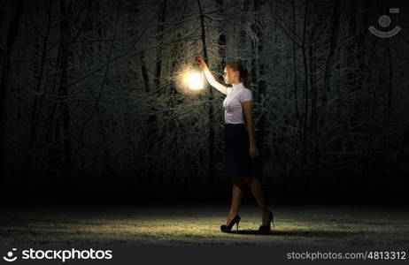 Businesswoman with lantern. Young businesswoman walking in darkness with lantern in hand