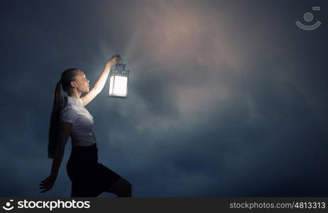 Businesswoman with lantern. Young businesswoman walking in darkness with lantern in hand