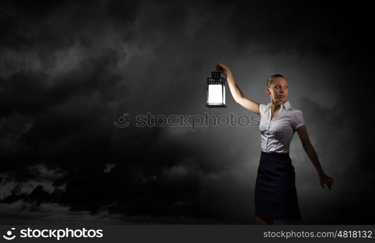 Businesswoman with lantern. Young businesswoman walking in darkness with lantern in hand