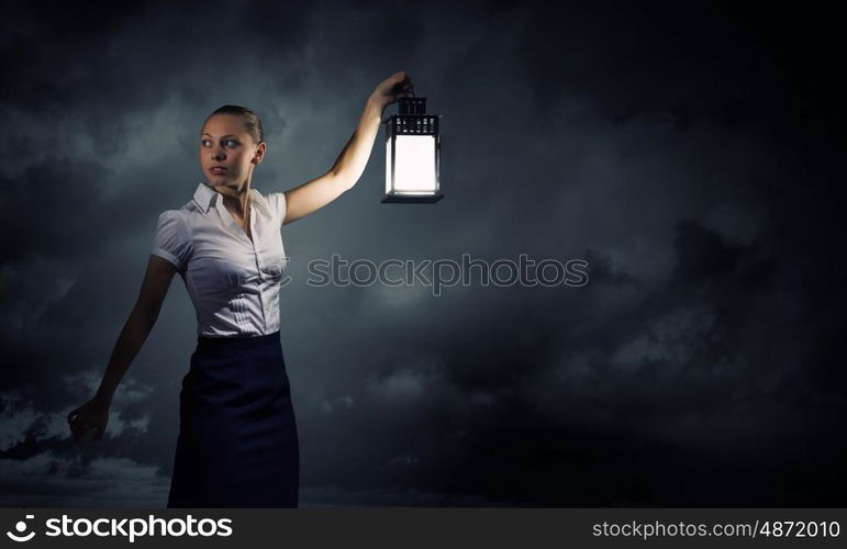 Businesswoman with lantern. Young businesswoman walking in darkness with lantern in hand