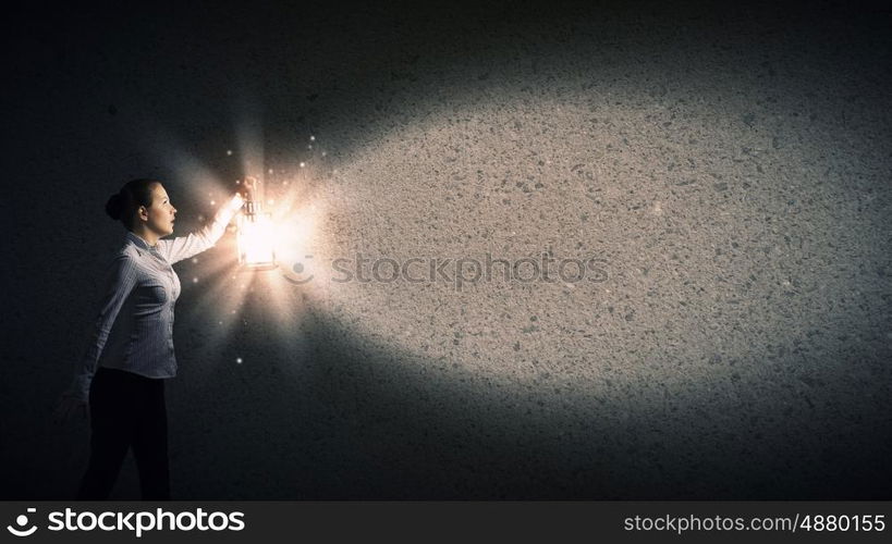 Businesswoman with lantern. Young businesswoman walking in darkness with lantern in hand