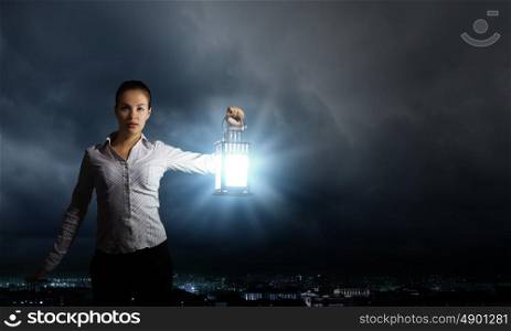 Businesswoman with lantern. Young businesswoman walking in darkness with lantern in hand