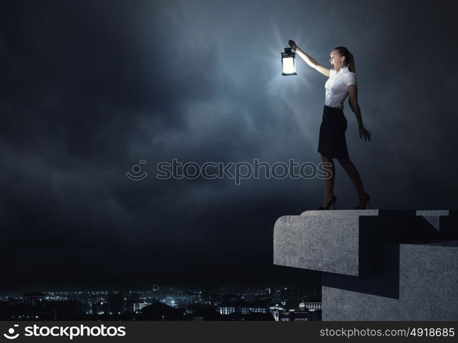 Businesswoman with lantern. Young businesswoman walking in darkness with lantern in hand