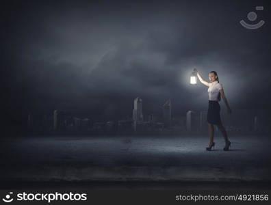 Businesswoman with lantern. Young businesswoman walking in darkness with lantern in hand