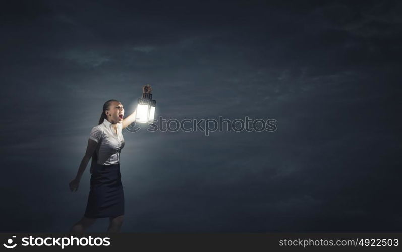 Businesswoman with lantern. Young businesswoman walking in darkness with lantern in hand