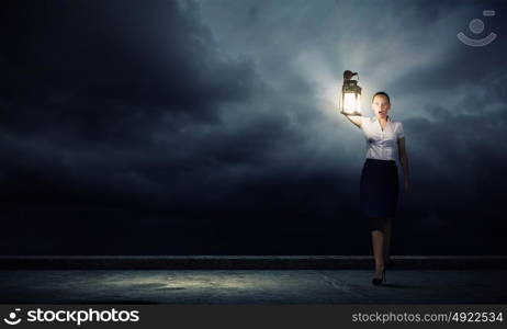 Businesswoman with lantern. Young businesswoman walking in darkness with lantern in hand