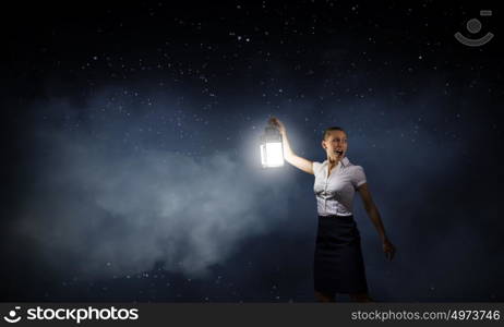 Businesswoman with lantern. Young businesswoman walking in darkness with lantern in hand