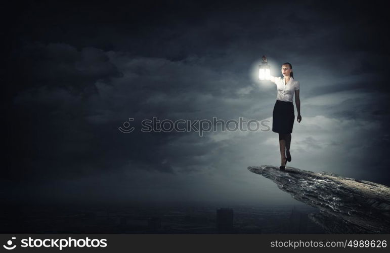 Businesswoman with lantern. Young businesswoman walking in darkness with lantern in hand