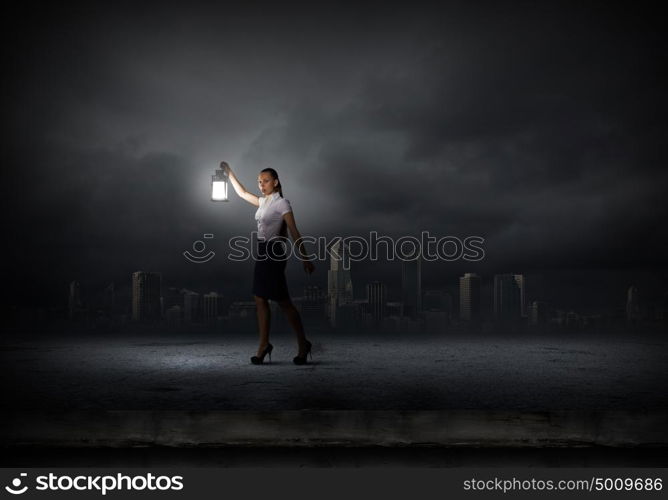 Businesswoman with lantern. Young businesswoman walking in darkness with lantern in hand