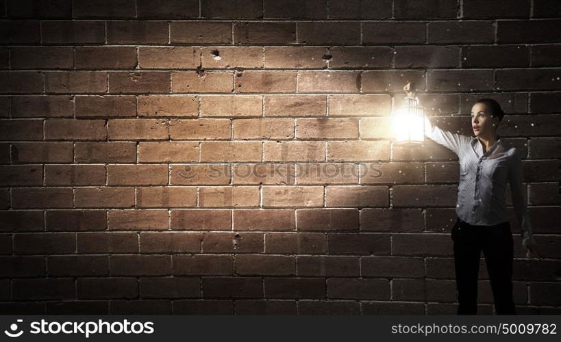 Businesswoman with lantern. Young businesswoman walking in darkness with lantern in hand