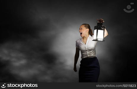 Businesswoman with lantern. Young businesswoman walking in darkness with lantern in hand