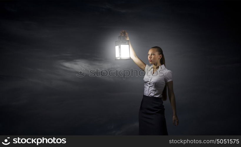 Businesswoman with lantern. Young businesswoman walking in darkness with lantern in hand