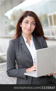 Businesswoman with laptop computer standing outside