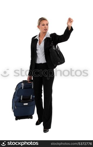 Businesswoman with luggage hailing taxi