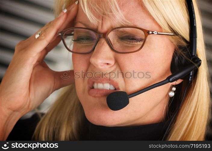 Businesswoman with phone headset show signs of having a headache.