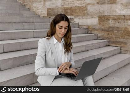 businesswoman with smartwatch working laptop while sitting stairs