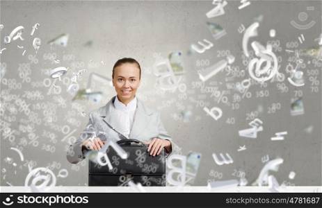 Businesswoman with suitcase. Young pretty businesswoman sitting with briefcase in hands