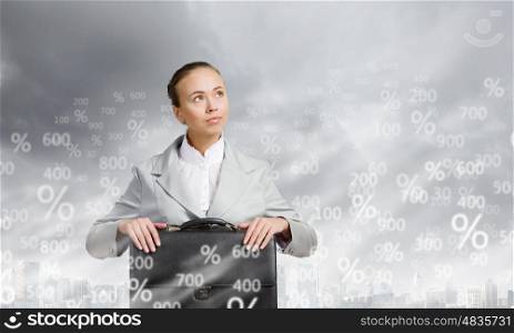 Businesswoman with suitcase. Young pretty businesswoman sitting with briefcase in hands