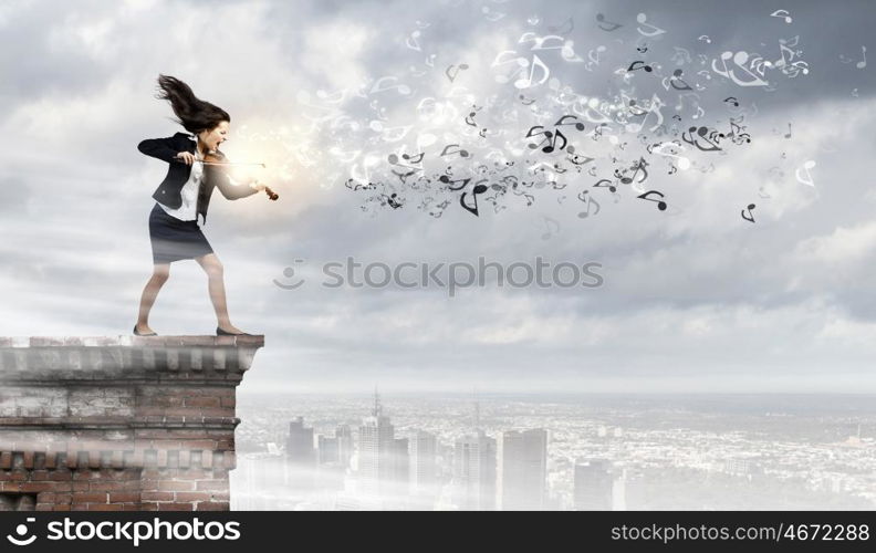 Businesswoman with violin. Young determined woman in black suit playing violin