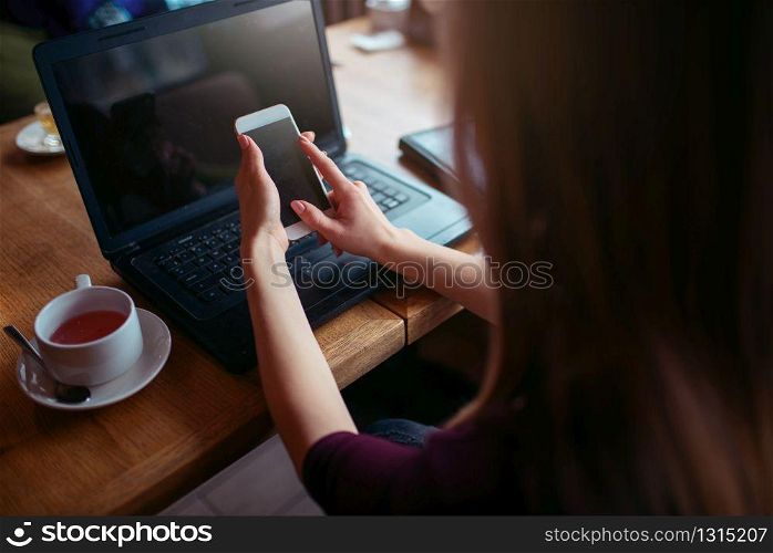 Businesswoman work in cafe using internet technology. Young woman with phone and laptop. Business people lifestyle.