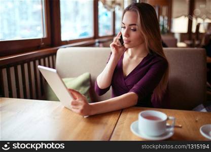 Businesswoman work in cafe using internet technology. Young woman with phone and tablet pc.