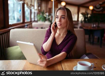 Businesswoman work in cafe using internet technology. Young woman with phone and tablet pc. Businesswoman work in cafe