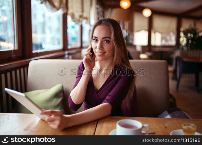 Businesswoman work in cafe using internet technology. Young woman with phone and tablet pc. Businesswoman work in cafe