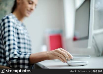 Businesswoman Working At Computer Wirelessly Charging Mobile Phone