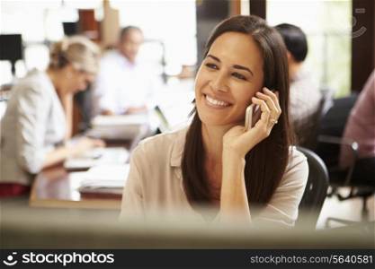 Businesswoman Working At Desk Using Mobile Phone