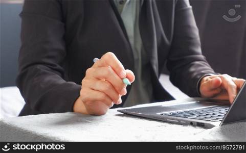Businesswoman working in front of laptop and hand holding a pen suitable for making infographics