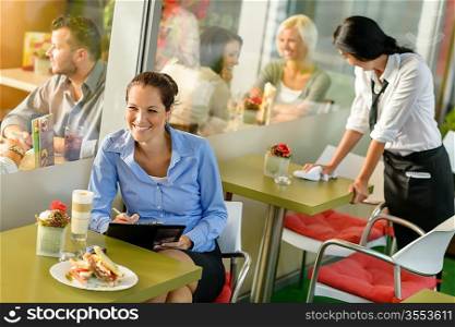 Businesswoman working in lunch break in cafe writing happy inspiration
