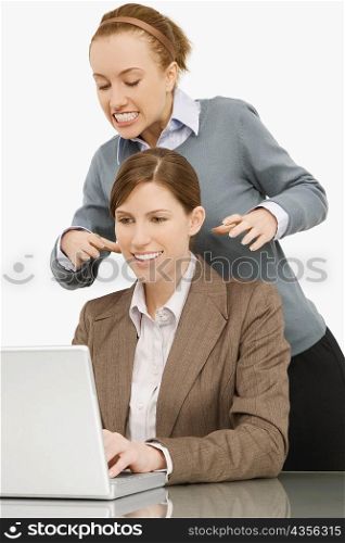 Businesswoman working on a laptop with her colleague try to strangle behind her