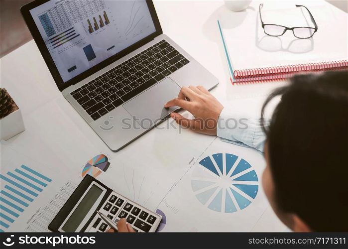 businesswoman working on desk using calculator and laptop analyzing finance accounting in office
