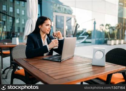 Businesswoman works on laptop in office, top view. Modern building, financial center, cityscape. Female businessperson in suit at workplace. Businesswoman works on laptop in office, top view