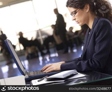 Businesswoman works on laptop in the lobby.