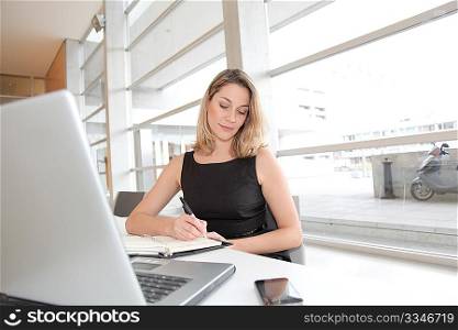 Businesswoman writing appointment on agenda