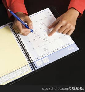 Businesswoman writing in appointment calendar.