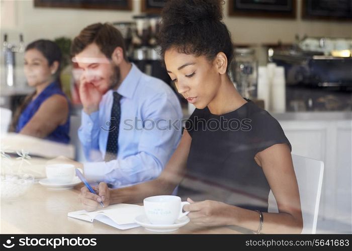 Businesswoman Writing Notes In Coffee Shop