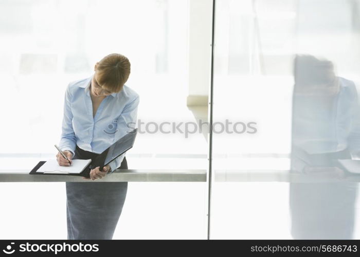 Businesswoman writing on document in office