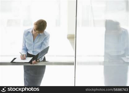 Businesswoman writing on document in office