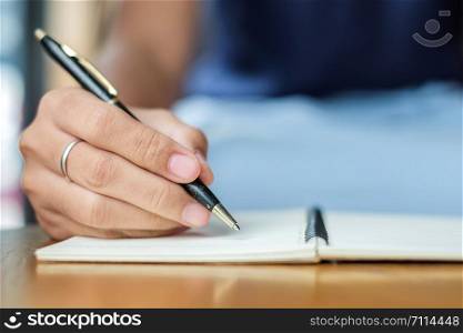 Businesswoman writing something on notebook in office, hand of woman holding pen with signature on paper report. business concepts
