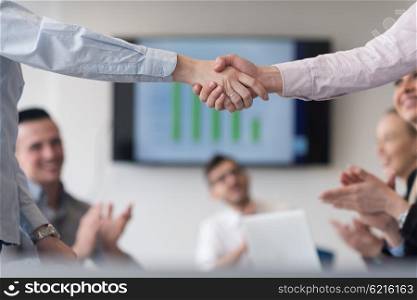 businesswomans handshake on team meeting with group of people blured in background at modern startup business office interior